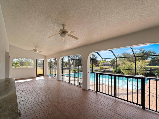 pool featuring a patio area, glass enclosure, and a ceiling fan