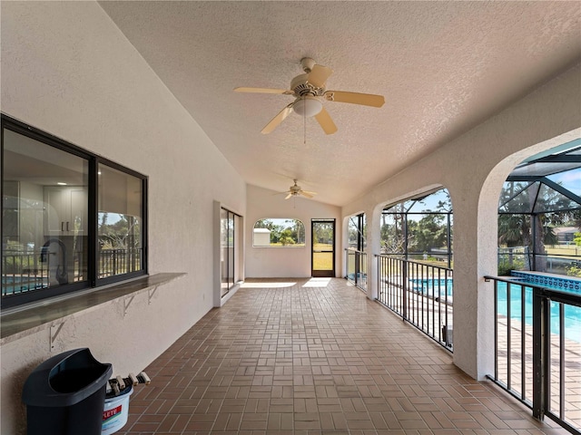 view of patio with glass enclosure, an outdoor pool, and ceiling fan