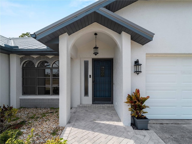 view of exterior entry featuring stucco siding and an attached garage