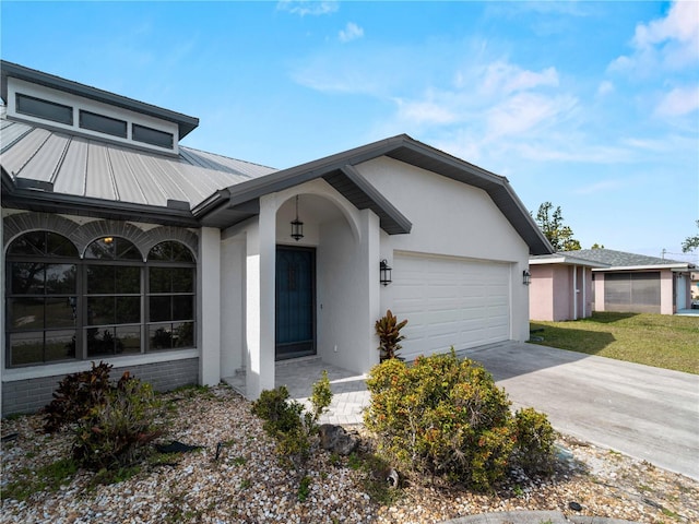 view of front of home featuring stucco siding, a garage, metal roof, and concrete driveway