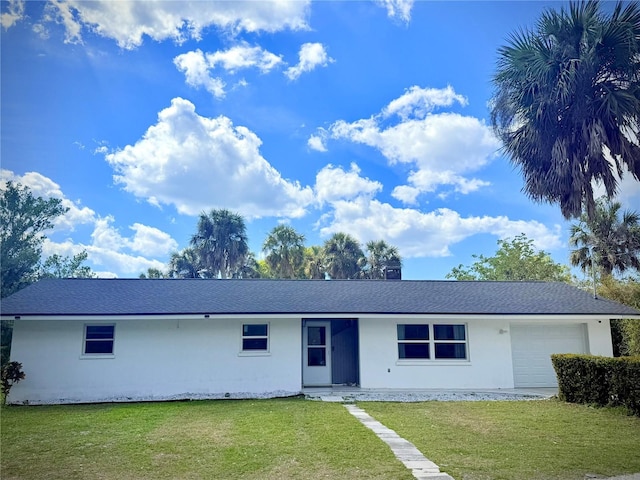 ranch-style house with stucco siding, an attached garage, a front yard, and roof with shingles