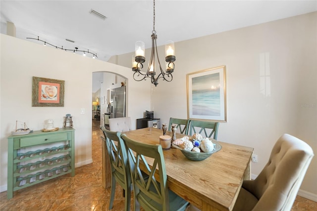 dining room featuring arched walkways, visible vents, rail lighting, and an inviting chandelier