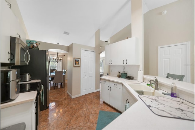 kitchen with a sink, stainless steel microwave, white cabinetry, and light countertops