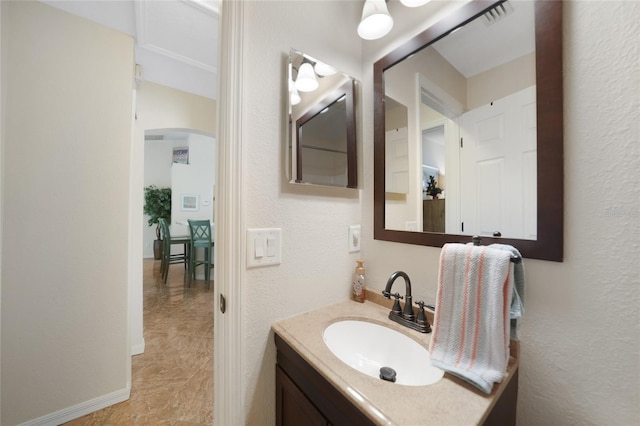 bathroom with vanity, a textured wall, visible vents, and baseboards