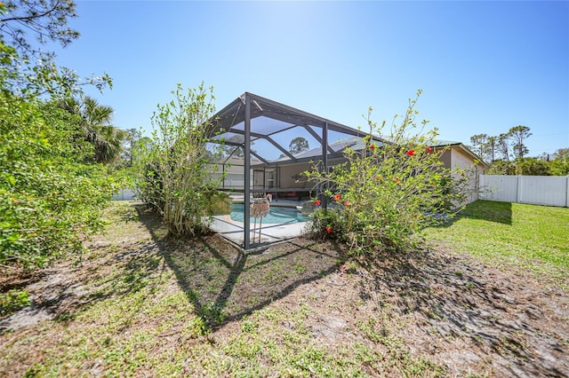 view of yard featuring an outdoor pool, glass enclosure, a fenced backyard, and a patio area