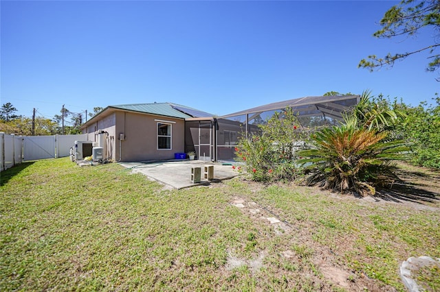 rear view of house with a lanai, a lawn, a fenced backyard, a patio area, and a gate