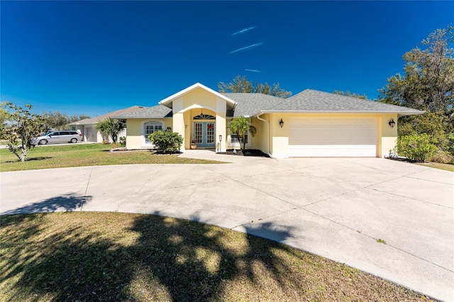 view of front of house featuring a front lawn, stucco siding, french doors, a garage, and driveway