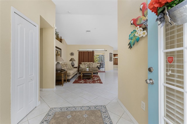 foyer entrance featuring light tile patterned floors, lofted ceiling, and baseboards