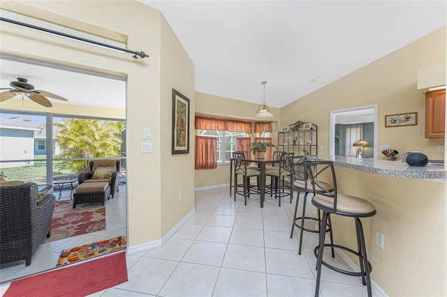 dining area featuring light tile patterned floors, baseboards, lofted ceiling, and a ceiling fan