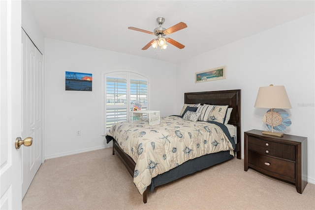 bedroom featuring baseboards, light carpet, a closet, and a ceiling fan