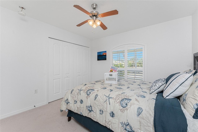 carpeted bedroom with a closet, baseboards, and ceiling fan