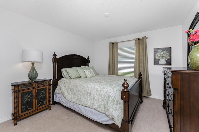 bedroom with light colored carpet and baseboards