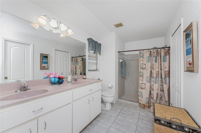 bathroom featuring a sink, visible vents, tiled shower, and toilet