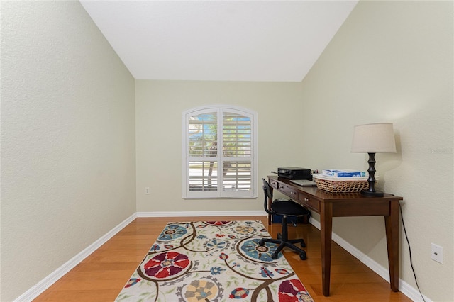 home office with vaulted ceiling, light wood-style floors, and baseboards