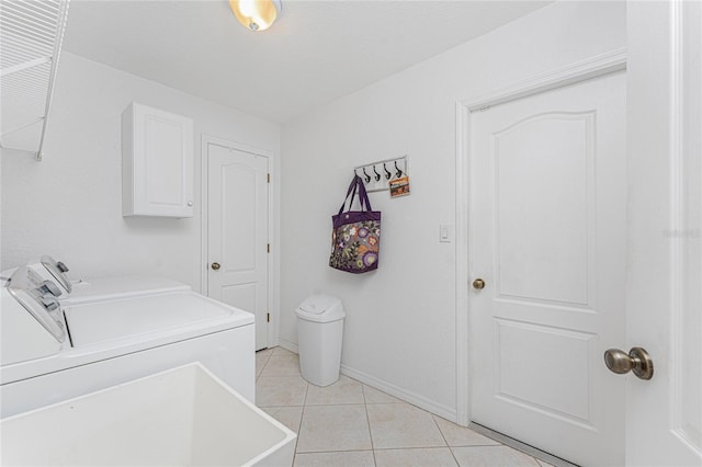 clothes washing area featuring washer and dryer, light tile patterned floors, cabinet space, and baseboards