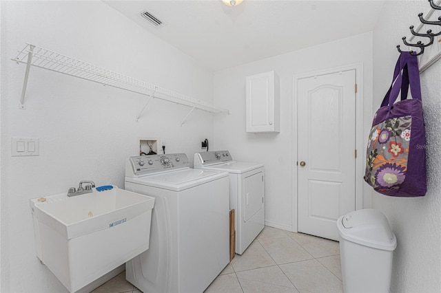 clothes washing area featuring light tile patterned floors, visible vents, washing machine and clothes dryer, laundry area, and a sink