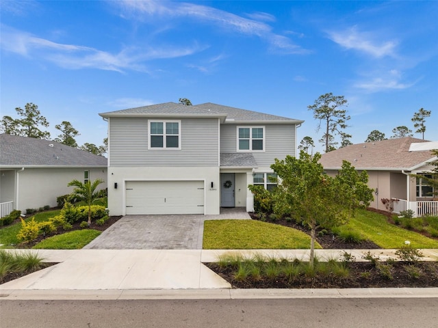 view of front of home with an attached garage, decorative driveway, and a front yard