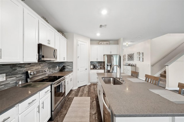 kitchen featuring visible vents, an island with sink, a sink, stainless steel appliances, and decorative backsplash