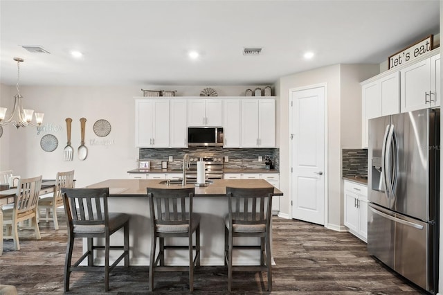 kitchen featuring visible vents, a kitchen bar, appliances with stainless steel finishes, and dark wood-style floors