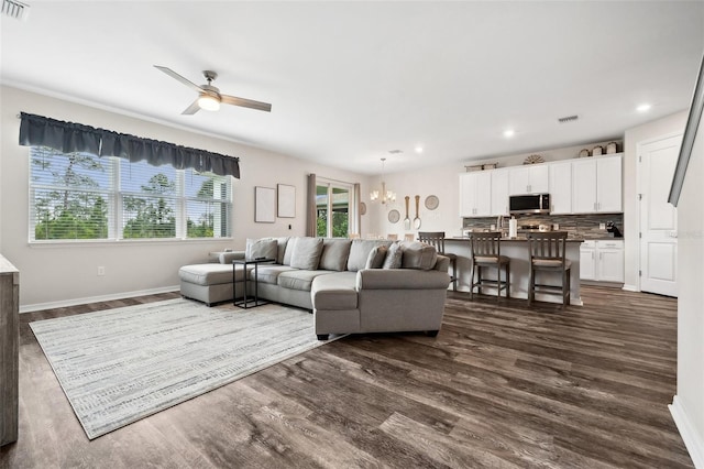 living room with visible vents, baseboards, dark wood finished floors, and ceiling fan with notable chandelier