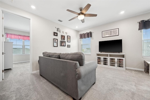 living room with a wealth of natural light, visible vents, ceiling fan, and carpet flooring