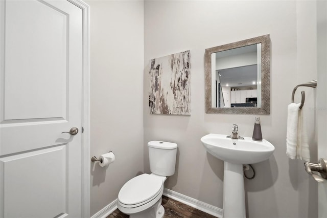 bathroom with a sink, baseboards, toilet, and wood finished floors