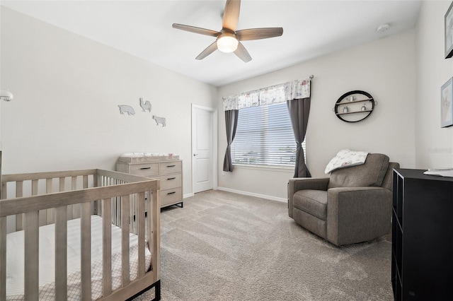 carpeted bedroom with ceiling fan, baseboards, and a nursery area