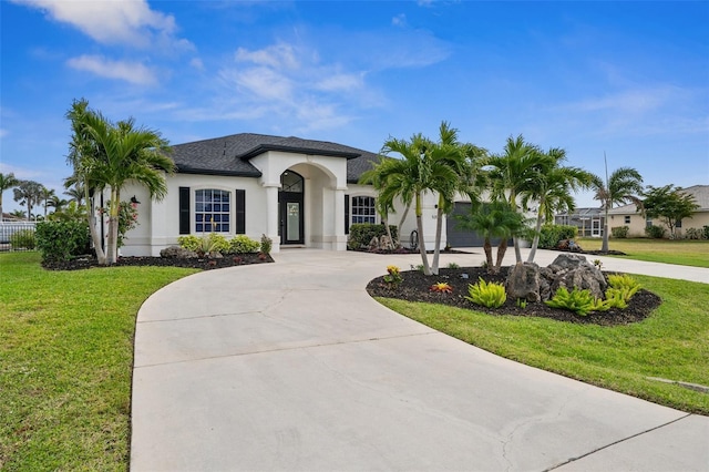 view of front of property with stucco siding, curved driveway, a front lawn, and a shingled roof