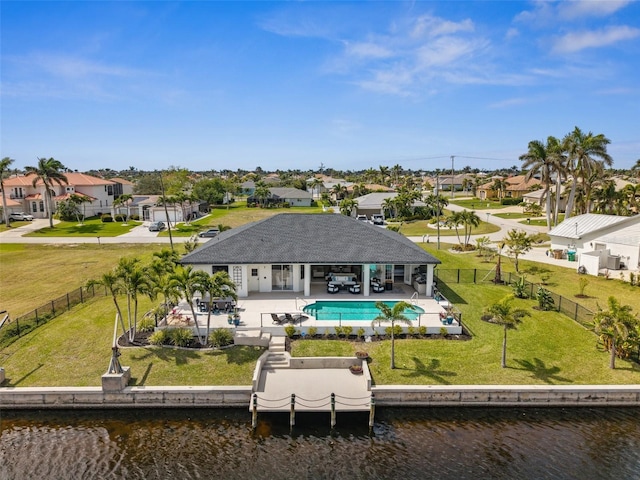 back of house with a yard, a residential view, a fenced backyard, and a water view