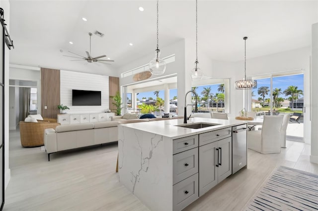 kitchen featuring light wood finished floors, gray cabinetry, light stone countertops, recessed lighting, and a sink