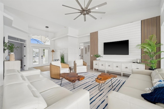 living area featuring french doors, a towering ceiling, and a ceiling fan