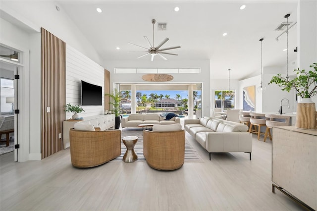 living area with recessed lighting, visible vents, a high ceiling, and light wood finished floors