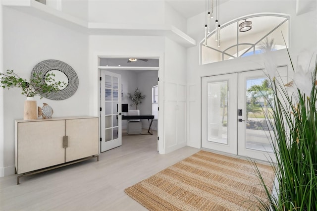 entrance foyer featuring wood finished floors, french doors, visible vents, and a towering ceiling