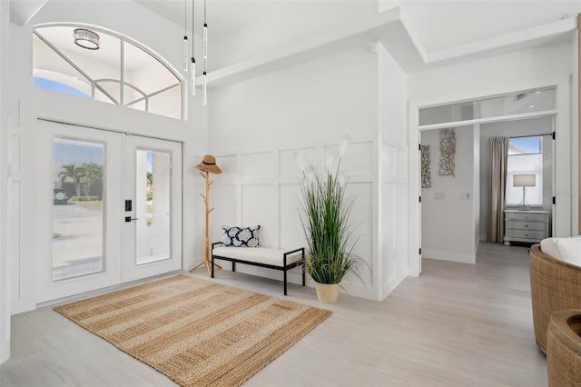 entryway with a decorative wall, french doors, a wainscoted wall, and wood finished floors