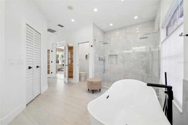 full bathroom featuring a freestanding tub, visible vents, toilet, a closet, and a shower stall