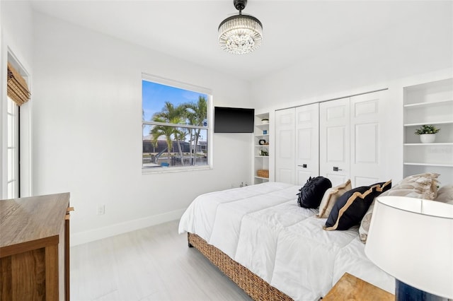 bedroom featuring a closet, baseboards, an inviting chandelier, and wood finished floors