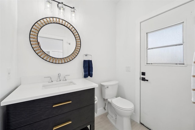 bathroom with baseboards, toilet, and vanity