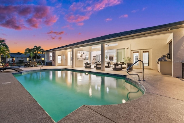 pool at dusk featuring a patio area, french doors, and an outdoor pool