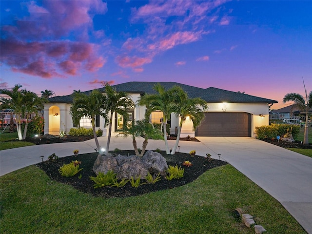 view of front facade with a yard, stucco siding, driveway, and a garage