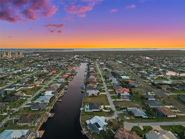 aerial view at dusk with a residential view and a water view