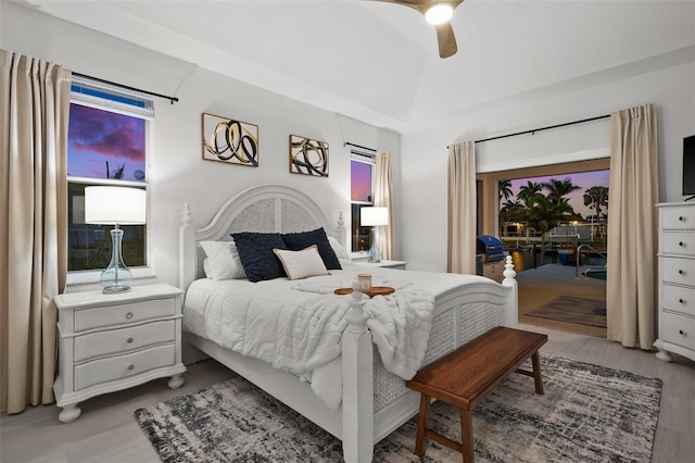 bedroom with wood finished floors, a ceiling fan, lofted ceiling, and access to outside