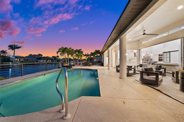 pool at dusk featuring a water view, an outdoor living space, an outdoor pool, ceiling fan, and a patio area