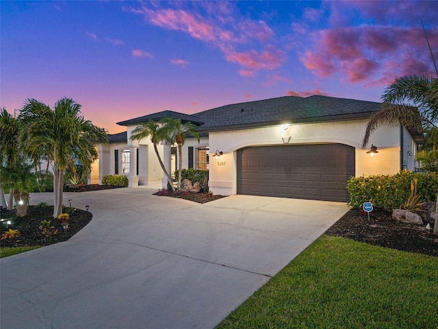 view of front of home featuring stucco siding, a garage, and driveway