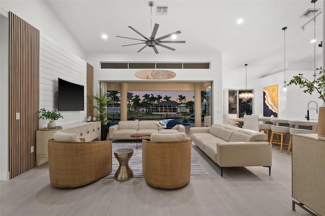 living area with a notable chandelier, visible vents, recessed lighting, and a high ceiling