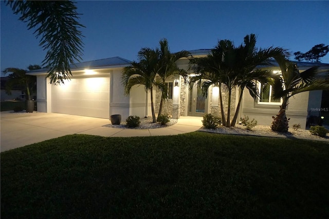 view of front of home featuring a yard, a garage, driveway, and stucco siding