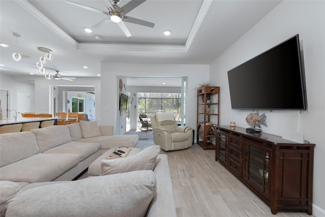 living room featuring ornamental molding, recessed lighting, light wood-style floors, a raised ceiling, and a ceiling fan