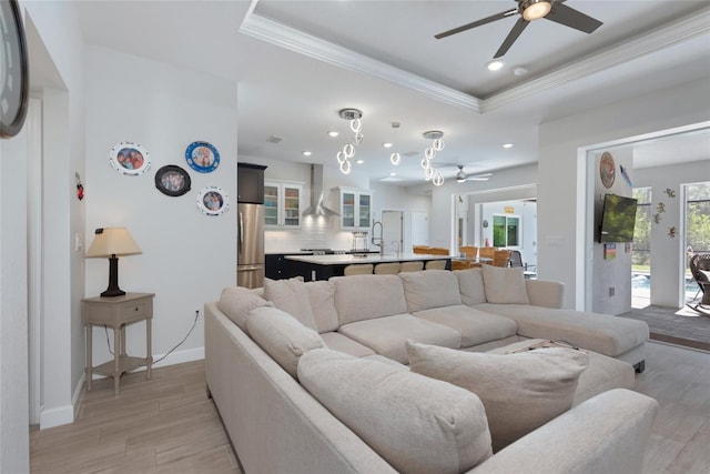 living room with crown molding, a raised ceiling, and baseboards