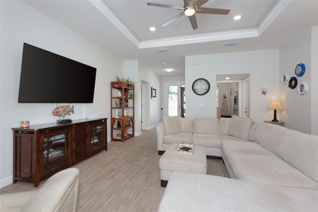 living room featuring baseboards, light wood-type flooring, ornamental molding, recessed lighting, and a raised ceiling