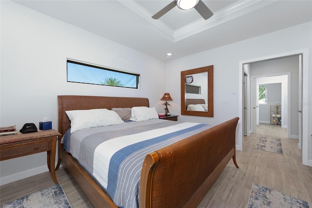 bedroom featuring a tray ceiling, light wood-type flooring, baseboards, and ceiling fan