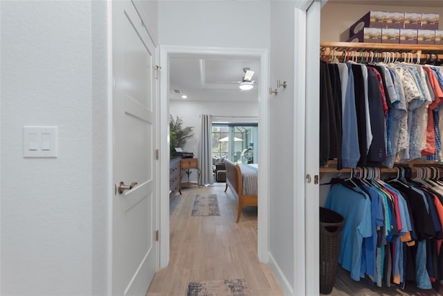 walk in closet with light wood finished floors and ceiling fan